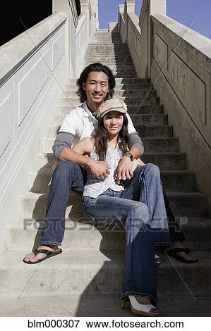 Stock Photo - Korean couple sitting on stairway outdoors. Fotosearch