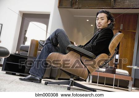 Korean man sitting in chair in living room View Large Photo Image Stock Photo - Korean man sitting in chair in living room. Fotosearch