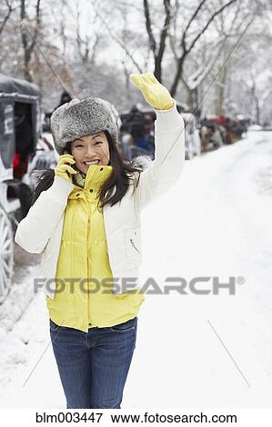 Stock Photo - Korean woman talking on cell phone on snowy day. Fotosearch