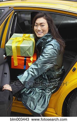 Stock Image - Korean woman with gifts taking taxi. Fotosearch