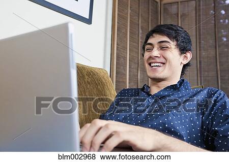 Laughing mixed race man typing on laptop View Large Photo Image Stock Photo - Laughing mixed race man typing on laptop. Fotosearch