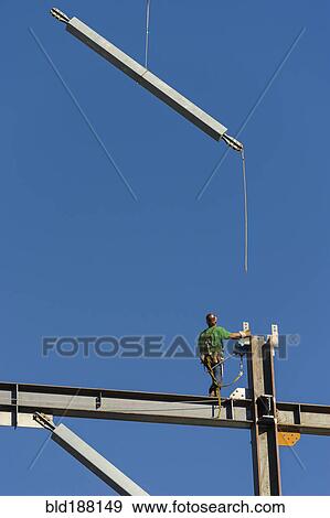 Stock Photo - Low angle view of construction worker on scaffolding. Fotosearch