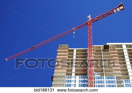 Stock Image - Low angle view of crane building highrise. Fotosearch
