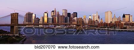 Stock Image - Lower Manhattan Skyline and Brooklyn Bridge at Dawn. Fotosearch