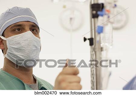 Stock Image - Male doctor adjusting IV. Fotosearch