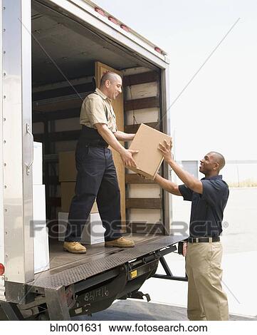 Stock Image - Male warehouse worker handing box off truck. Fotosearch