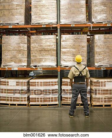 Male warehouse worker looking at stacks of boxes View Large Photo Image Stock Photograph - Male warehouse worker looking at stacks of boxes. Fotosearch