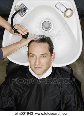 Stock Image - Man having hair washed at salon. Fotosearch