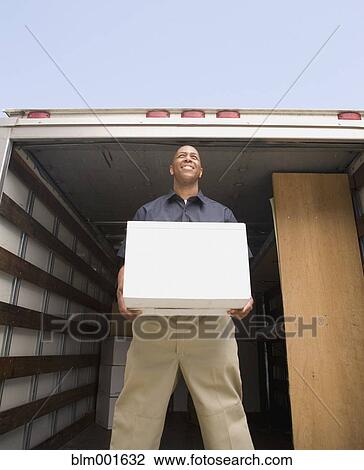 Stock Image - Man holding box on truck. Fotosearch