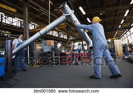 Stock Photography - Man moving metal piping in warehouse. Fotosearch