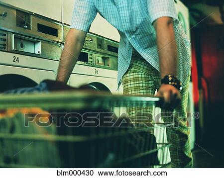 Man pushing laundry basket in laundromat View Large Photo Image Stock Image - Man pushing laundry basket in laundromat. Fotosearch