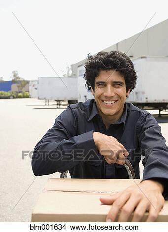 Picture - Man pushing stack of boxes on hand truck. Fotosearch