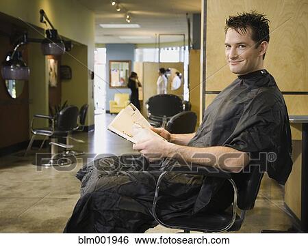Stock Photograph - Man reading in hair salon chair. Fotosearch