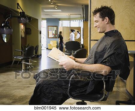 Stock Photography - Man reading in hair salon chair. Fotosearch