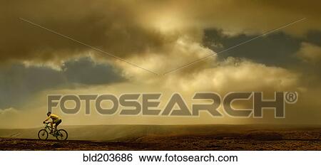 Stock Photograph - Man riding bicycle on dirt road. Fotosearch