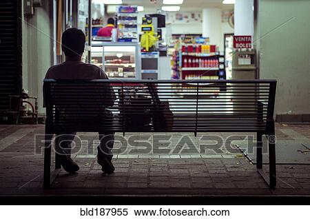 Stock Photography - Man sitting on city bench at night. Fotosearch