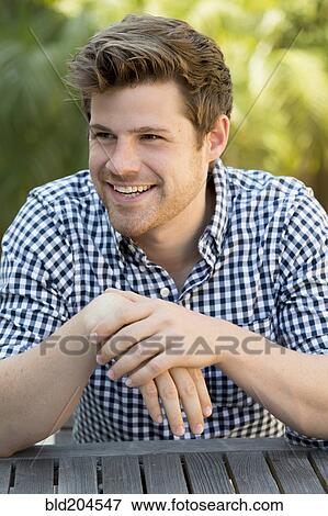 Stock Photo - Man sitting outdoors. Fotosearch