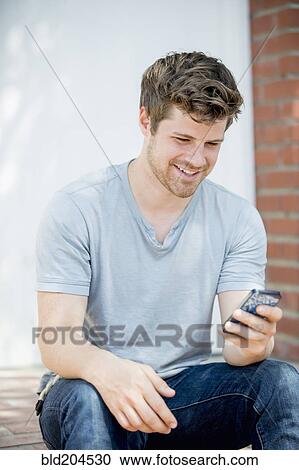 Stock Image - Man using cell phone outdoors. Fotosearch