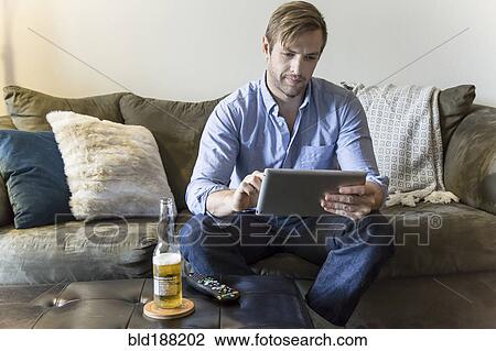 Man using digital tablet on sofa View Large Photo Image Stock Image - Man using digital tablet on sofa. Fotosearch