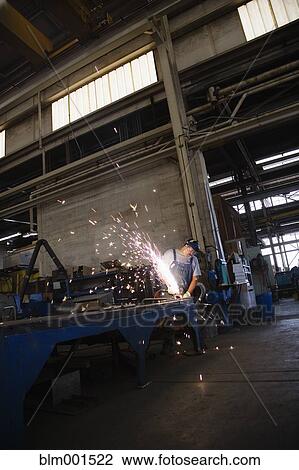 Stock Image - Man working on metal and creating sparks. Fotosearch