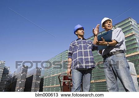 Stock Image - Manager talking with worker at processing plant. Fotosearch