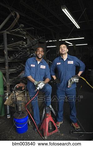 Stock Image - Mechanics working together in repair shop. Fotosearch