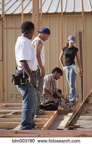 Stock Image - Men and woman working at construction site. Fotosearch