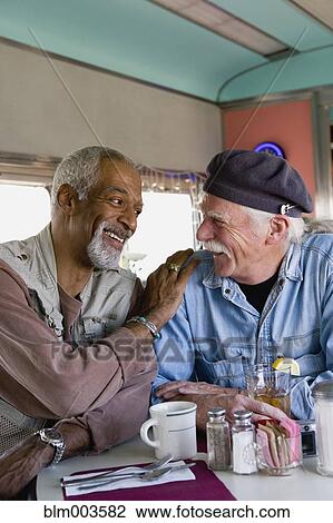 Stock Image - Men sitting at diner table. Fotosearch