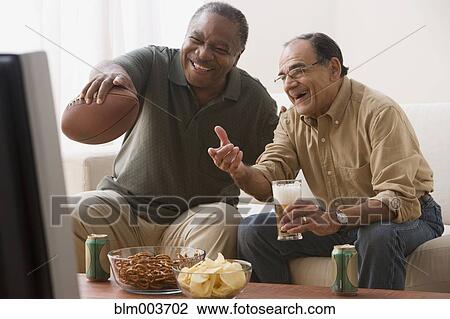 Men watching football game in living room with snacks View Large Photo Image Stock Image - Men watching football game in living room with snacks. Fotosearch