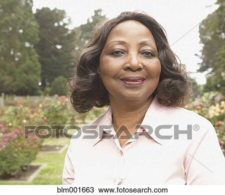 Stock Image - Middle-aged African woman smiling outdoors. Fotosearch
