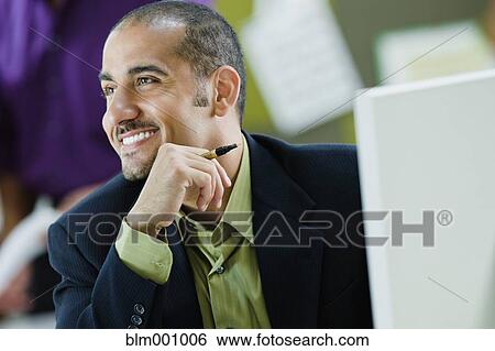 Stock Photograph - Middle Eastern businessman sitting at desk. Fotosearch