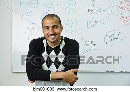 Stock Image - Middle Eastern man sitting near whiteboard. Fotosearch
