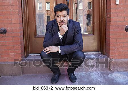 Stock Image - Middle Eastern man sitting on front stoop. Fotosearch