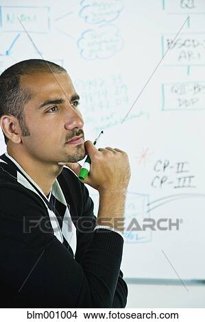 Picture - Middle Eastern man thinking near whiteboard. Fotosearch