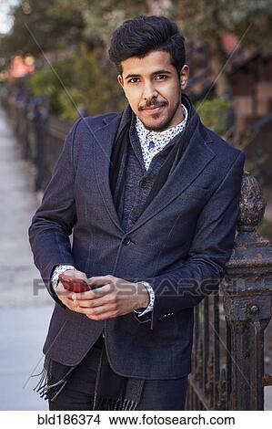Picture - Middle Eastern man using cell phone outdoors. Fotosearch