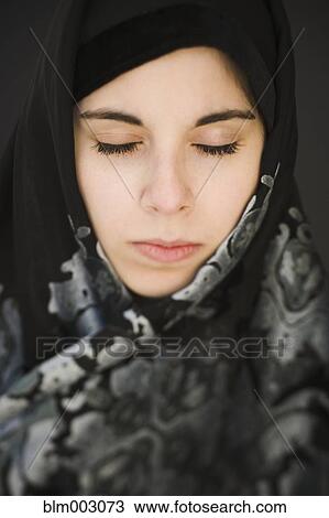 Stock Image - Middle Eastern teenager in headscarf with eyes closed. Fotosearch