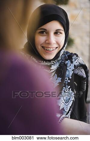 Stock Image - Middle Eastern teenager in headscarf talking to mother. Fotosearch