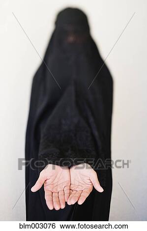 Stock Photograph - Middle Eastern woman in burka with hands outstretched. Fotosearch