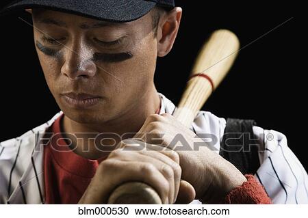 Stock Image - Mixed race baseball player holding bat. Fotosearch
