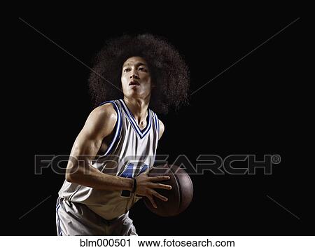 Stock Image - Mixed race basketball player holding basketball. Fotosearch
