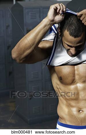 Stock Image - Mixed race basketball player undressing in locker room. Fotosearch
