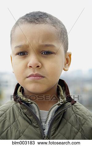 Stock Image - Mixed race boy frowning. Fotosearch