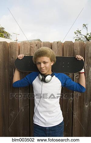 Mixed race boy in headphones holding skateboard View Large Photo Image Stock Image - Mixed race boy in headphones holding skateboard. Fotosearch