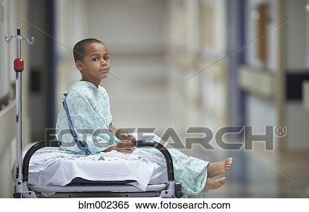 Stock Photography - Mixed Race boy in hospital gown. Fotosearch