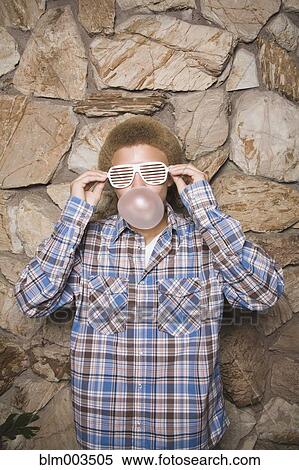 Stock Photography - Mixed race boy in sunglasses chewing bubble gum. Fotosearch