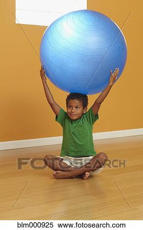 Stock Photography - Mixed race boy lifting exercise ball. Fotosearch