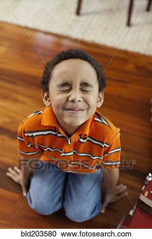Stock Image - Mixed race boy making a face on floor. Fotosearch