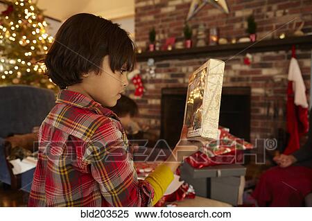 Stock Photography - Mixed race boy opening Christmas present. Fotosearch