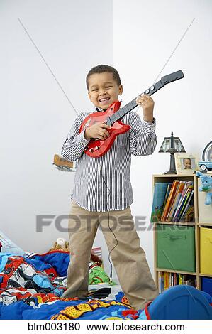 Stock Image - Mixed race boy playing toy guitar. Fotosearch