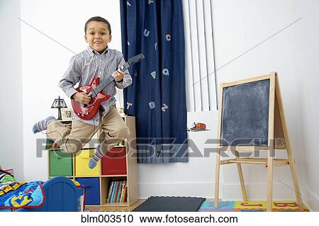 Mixed race boy playing toy guitar View Large Photo Image Stock Image - Mixed race boy playing toy guitar. Fotosearch